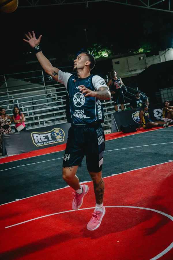 Jugador salta a lanzar el balón frente al cartel oficial del tour, RETO 3x3 Santa Marta 2026