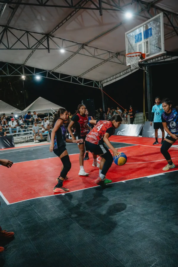 Jugadora U15 protege el balón bajo presión cerca del tablero de Santa Marta, RETO 3x3 2026