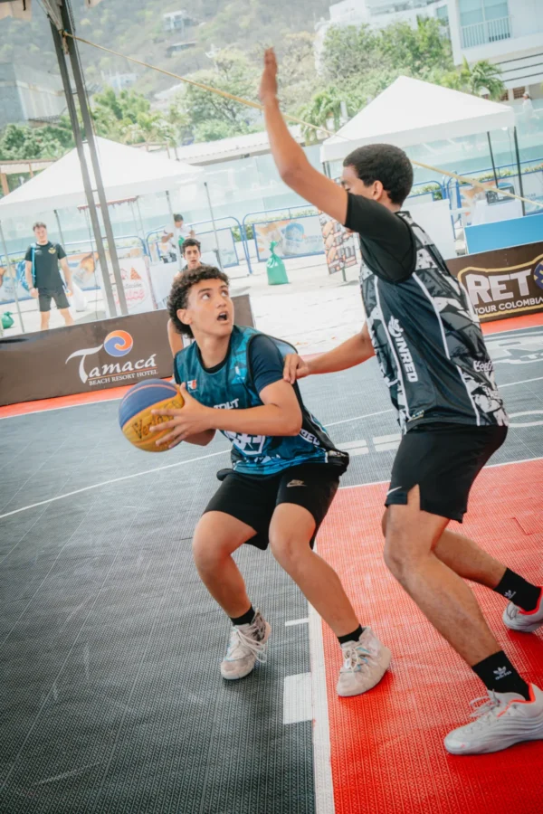 Jugador protege el balón con gesto intenso mientras un rival contesta el lanzamiento, RETO 3x3 Santa Marta 2026